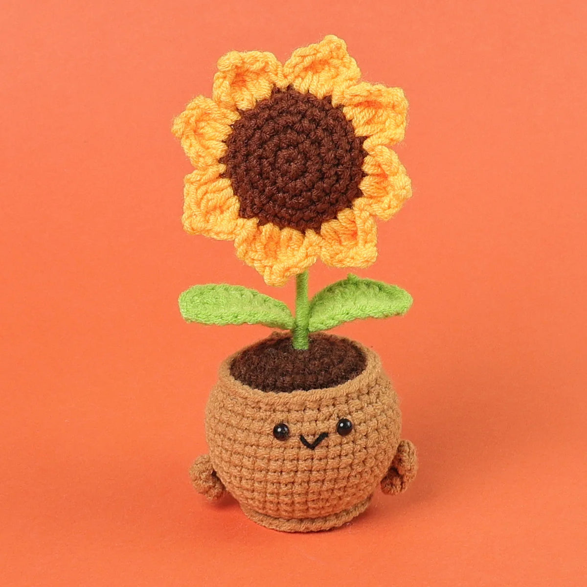 Handmade crochet sunflower desk companion with a smiling face, featuring orange petals and a brown center.