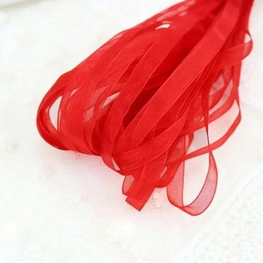 A bundle of bright red decorative fishtail yarn ribbon laid on a white surface.