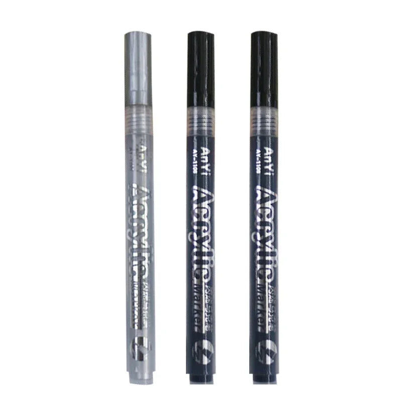 Three black acrylic paint pens with silver caps standing vertically.
