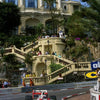 A Formula 1 race car drives on a track with a grand building in the background.