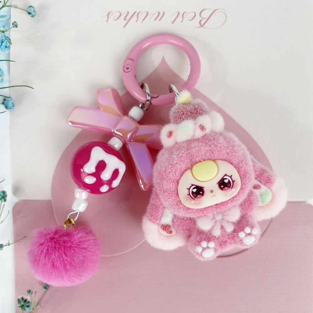 A pink fluffy heart plush keychain charm with a pink ring and a pink ribbon on a light pink background.