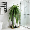 Artificial Persian fern hanging vine in a gold frame with white stones on a modern bathroom counter.