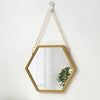 A gold-framed hexagon wall mirror hanging by a chain, with a small green plant visible inside.