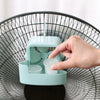 A hand places an ice cube into a teal portable cooling fan tray for fast cooling.
