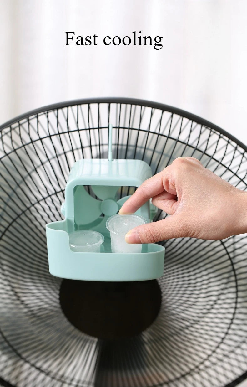 A hand places an ice cube into a teal portable cooling fan tray for fast cooling.