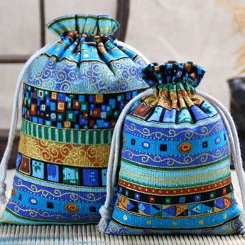 A close-up of a hand-stitched blue and gold patterned cotton drawstring gift pouch.