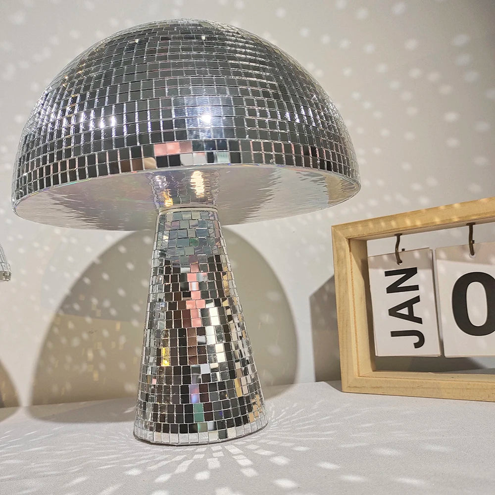A silver, mushroom-shaped disco ball decoration with a faceted glass base sits on a white surface.