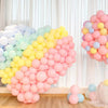 A large arrangement of pastel rainbow latex balloons in shades of pink, yellow, and blue for party décor.