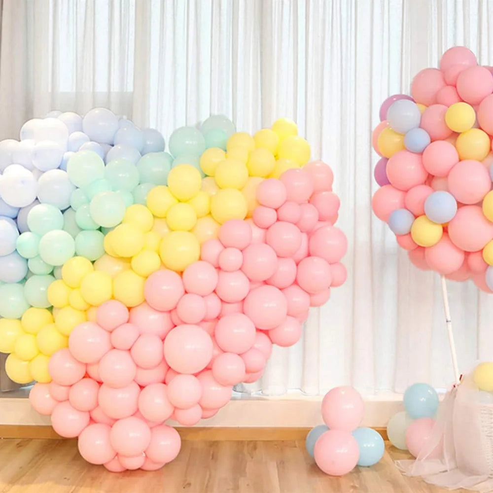 A large arrangement of pastel rainbow latex balloons in shades of pink, yellow, and blue for party décor.