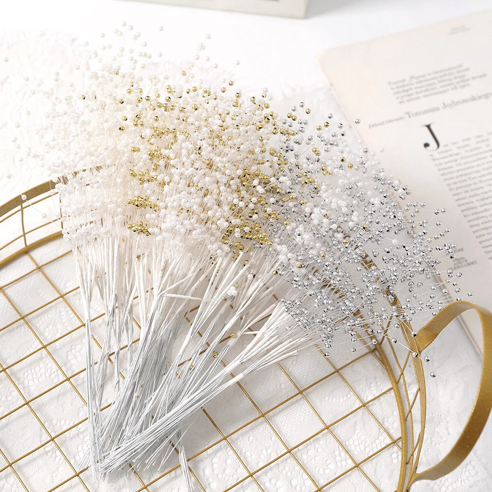 A bundle of pearl string beads scattered on a gold mesh tray next to a piece of paper.