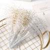 A bundle of pearl string beads scattered on a gold mesh tray next to a piece of paper.