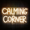 A glowing white neon sign spelling out CALMING CORNER hanging against a dark background.