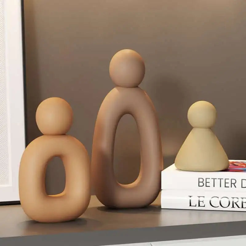 A set of three smooth, beige resin figures in a modern design standing on a surface.