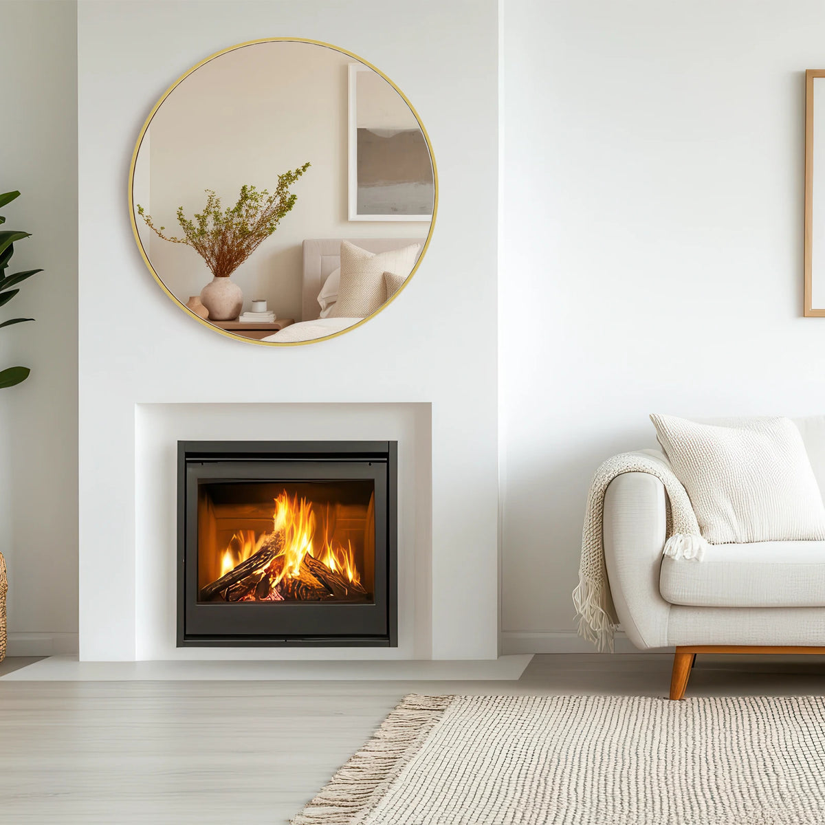 A large round vanity mirror with a matte metal frame hangs above a modern fireplace in a bright room.