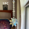 A clear crystal star pendant ornament hanging from a long chain, shown against a blurred indoor background.