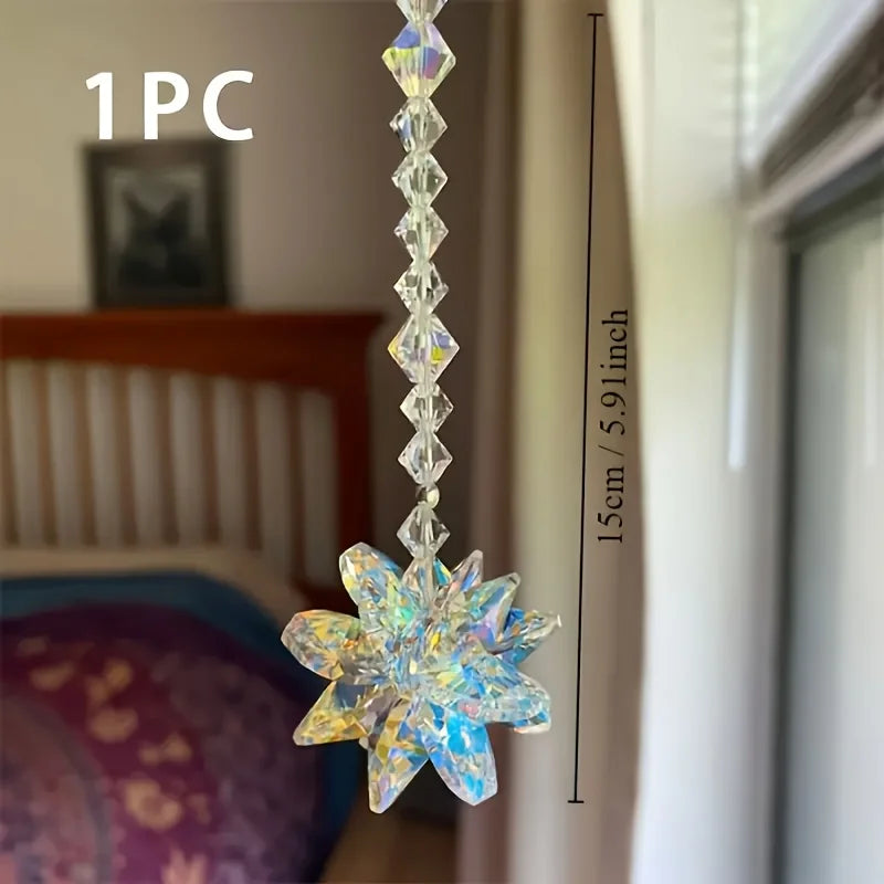 A clear crystal star pendant ornament hanging from a long chain, shown against a blurred indoor background.