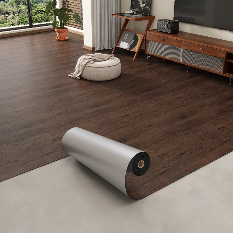 A close-up view of dark brown wood grain self-adhesive flooring film installed on a light beige floor.
