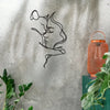 Black line art silhouette of a cat and woman embracing on a gray concrete wall with an orange lantern nearby.