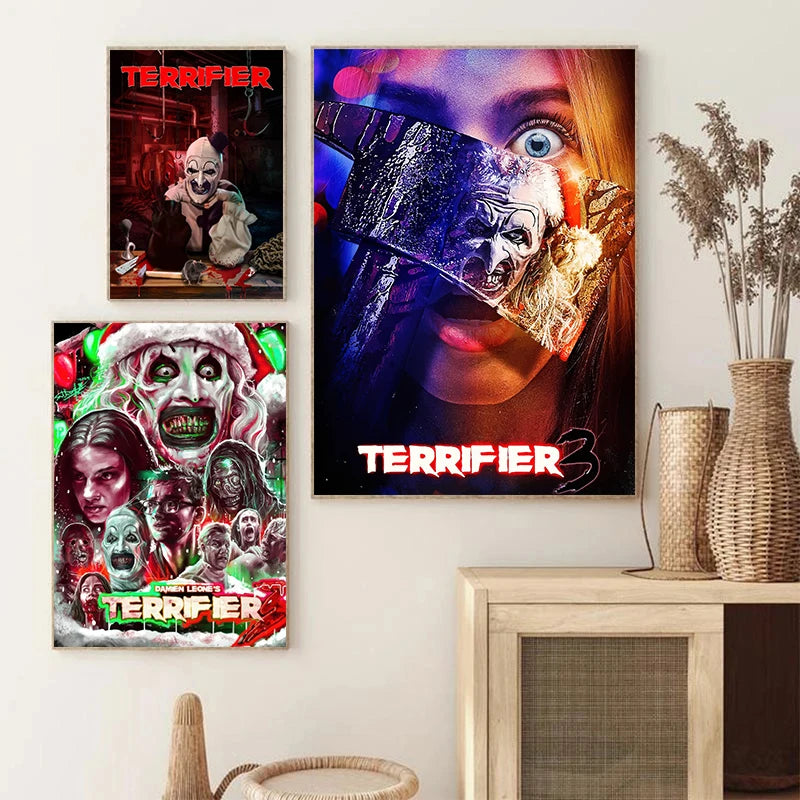 A set of three movie posters featuring characters from the Terrifier films displayed on a white wall.