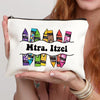 A beige floral canvas makeup bag with a zipper and colorful text reading Mtra. Itzel