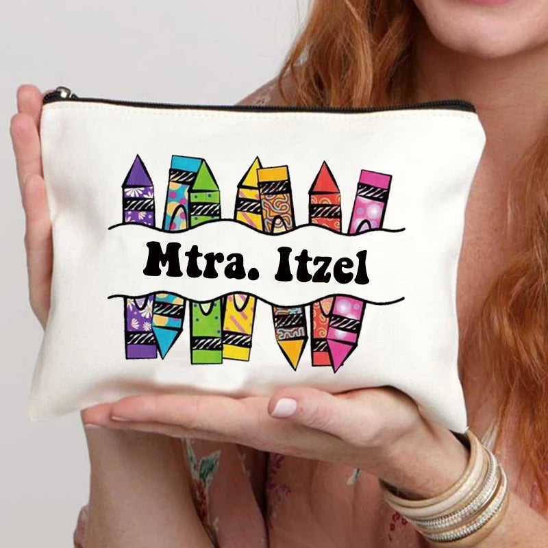 A beige floral canvas makeup bag with a zipper and colorful text reading Mtra. Itzel