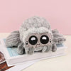A gray plush toy of Lucas the Spider with large eyes resting on a white book.