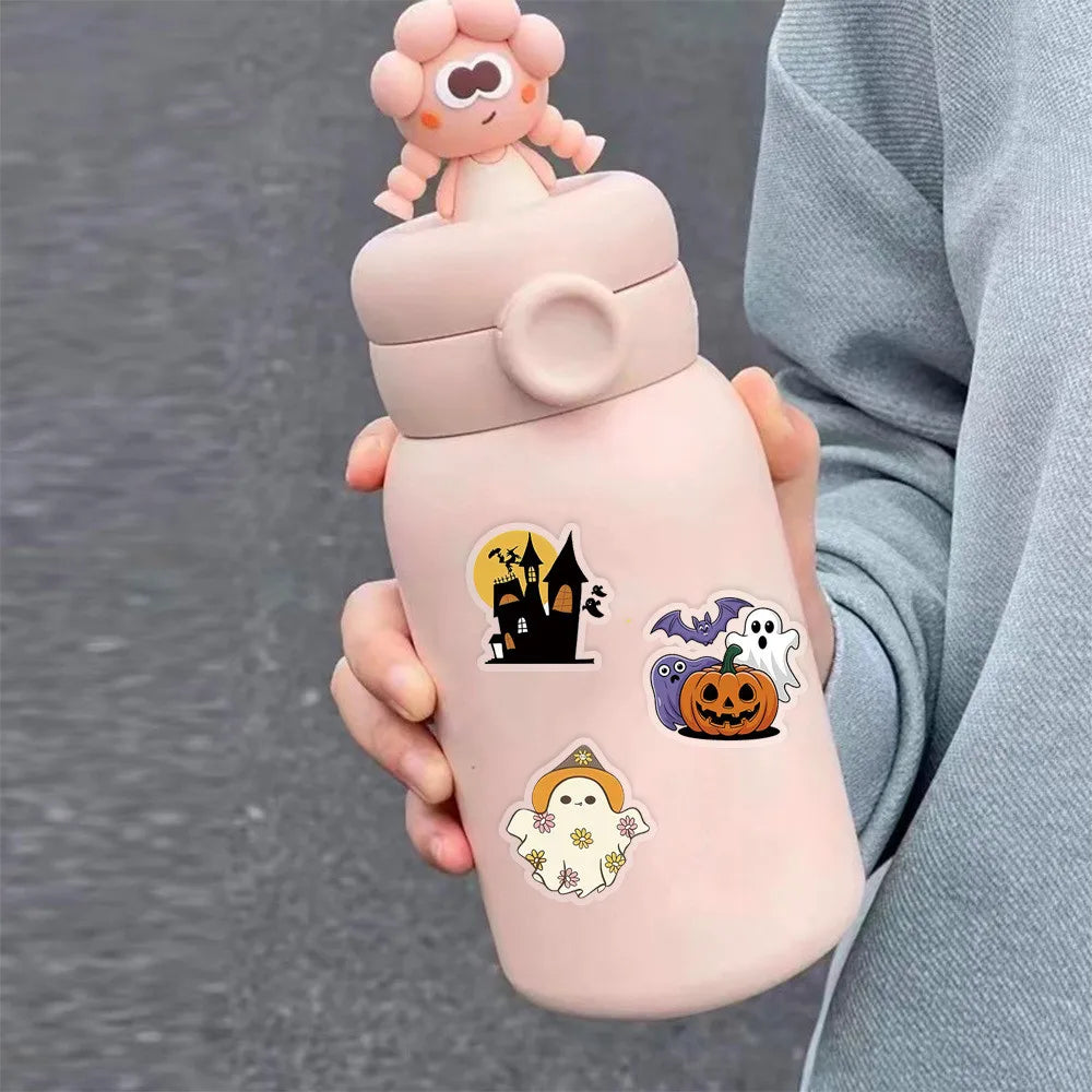 A hand holds a pink bottle with a lid and various Halloween-themed stickers on the body.