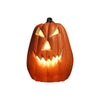 Calabaza de cerámica tallada con ojos amarillos brillantes y una sonrisa amenazante, usada como linterna de Halloween.