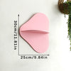 A pink cherry-shaped wooden wall shelf with a curved lip, mounted on a white wall.