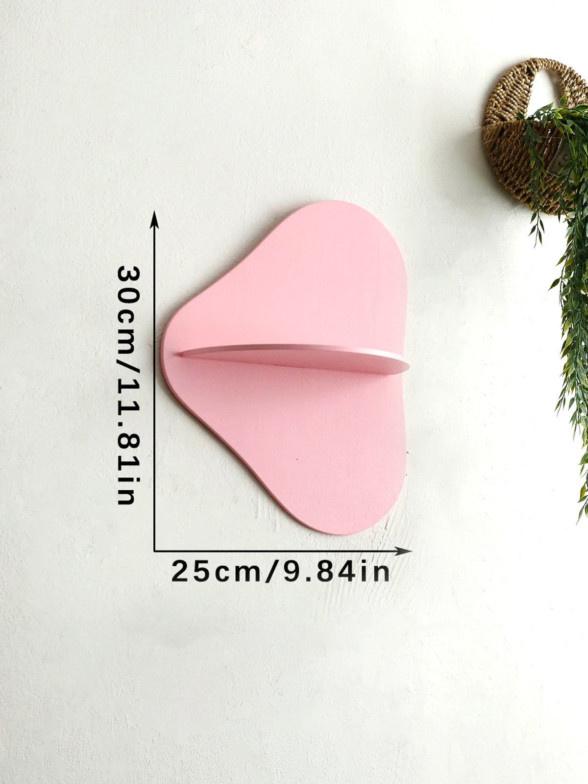 A pink cherry-shaped wooden wall shelf with a curved lip, mounted on a white wall.