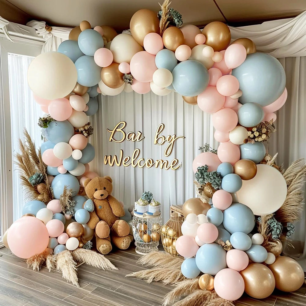 A floral arch made of assorted pastel latex balloons in pink, blue, and gold for a celebration backdrop.