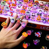 A hand holds a tray of Halloween glow rings featuring various spooky and cute faces, including pumpkins and ghosts.