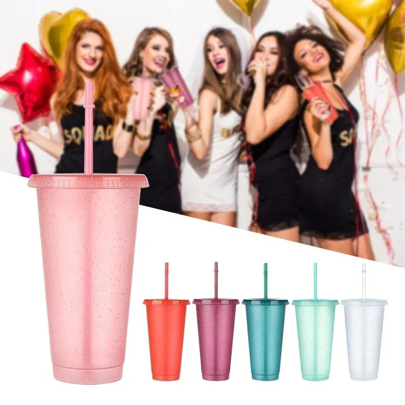 A group of women in black and white attire holding glitter party cups with lids and straws.