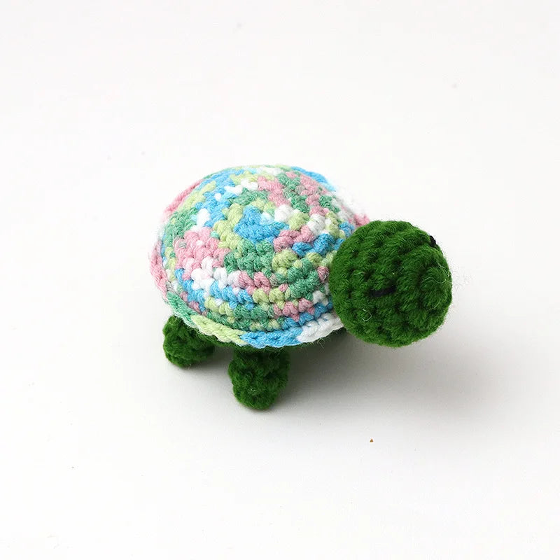 Handmade crocheted turtle plush with a multicolored shell and green body.