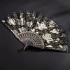 A vintage black and white lace folding fan decorated with roses and gold accents.