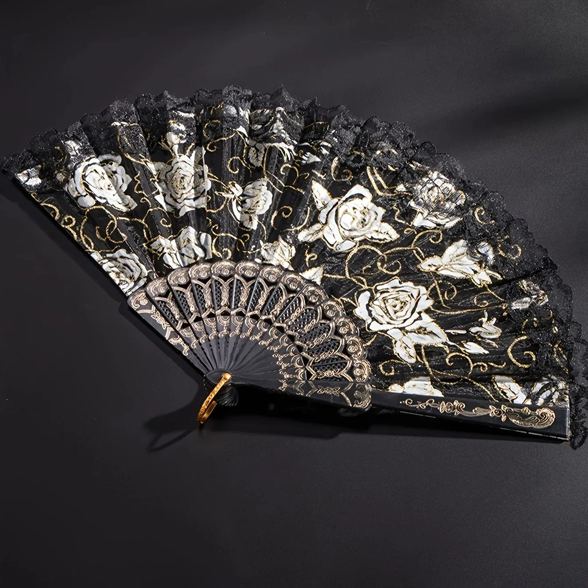 A vintage black and white lace folding fan decorated with roses and gold accents.