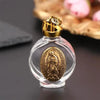 A clear glass bottle with a gold cap containing a religious sculpture inside.