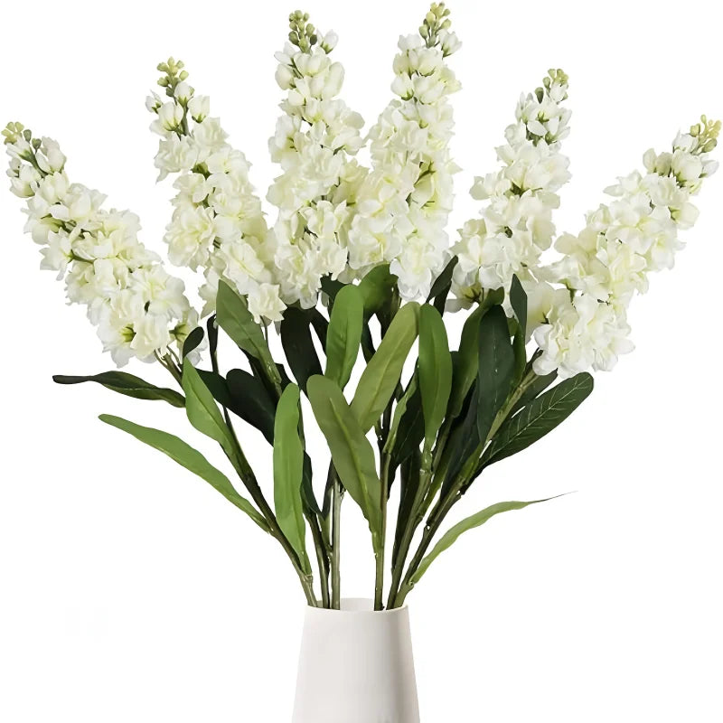 A bouquet of artificial white delphinium flowers with green leaves.