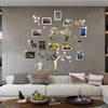 A family tree photo collage wall decoration featuring various framed photos and leaves on a gray wall.