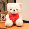 A fluffy white teddy bear plush toy with a red heart stitched onto its chest.