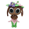 A plush toy resembling a stylized animal face with purple and green floral accents and pink clothing.