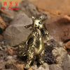 A vintage brass squirrel figurine standing on a rough, natural surface.