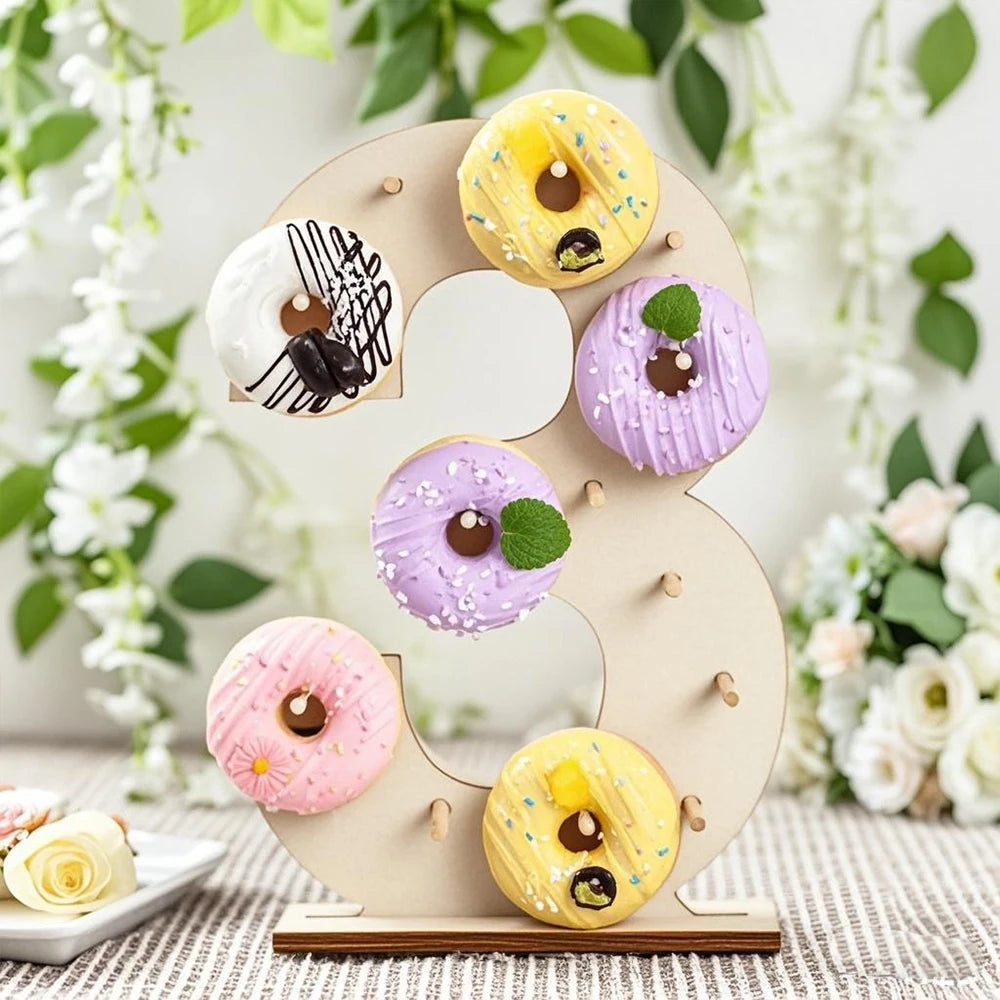 A wooden number display stand shaped like the number 3 holds various colorful frosted donuts.