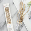 A set of six gold curved decorative birthday candles in a white box next to a page of text.