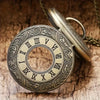 A vintage bronze quartz pocket watch with an ornate dial and chain resting on a wooden surface.