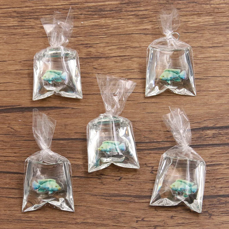 Un juego de bolsas de plástico transparente con pequeños adornos de resina en forma de pez payaso para hacer joyería