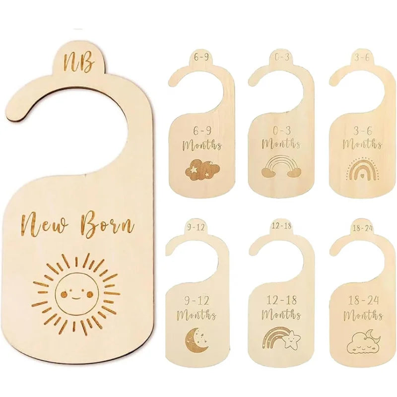 A set of seven wooden baby closet dividers featuring various age milestones and designs like clouds, rainbows, and suns.