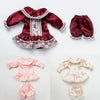 A vintage lace pajama set for a doll featuring a maroon top with white lace trim and matching bottoms.