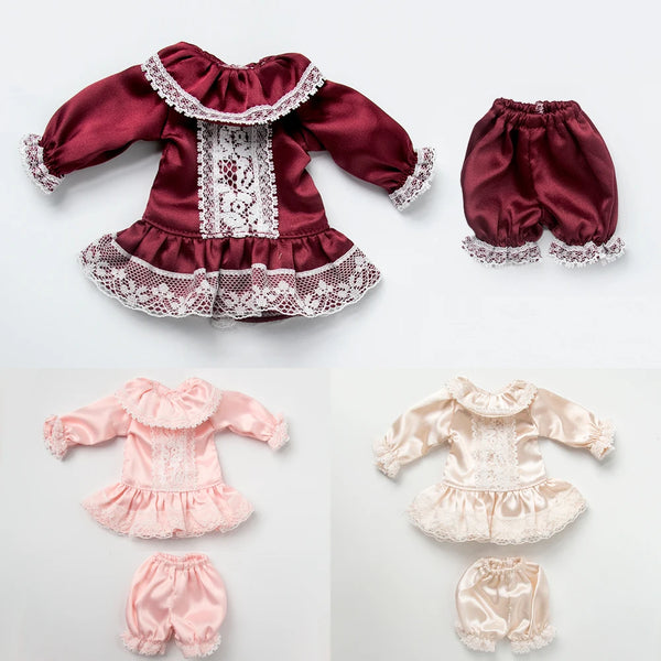A vintage lace pajama set for a doll featuring a maroon top with white lace trim and matching bottoms.