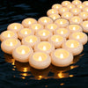 A row of floating, water-activated LED candles with warm flickering light reflecting on dark water.